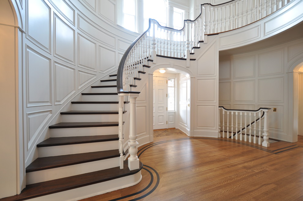 Modelo de escalera curva clásica grande con escalones de madera y contrahuellas de madera pintada