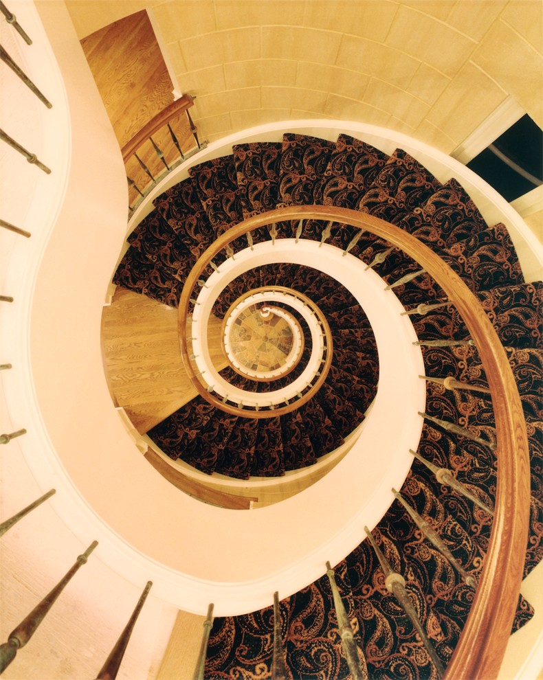 Large classic carpeted spiral staircase in Denver with carpeted risers.