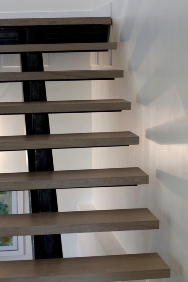 Immagine di una scala a "U" minimalista di medie dimensioni con pedata in legno, nessuna alzata e parapetto in metallo