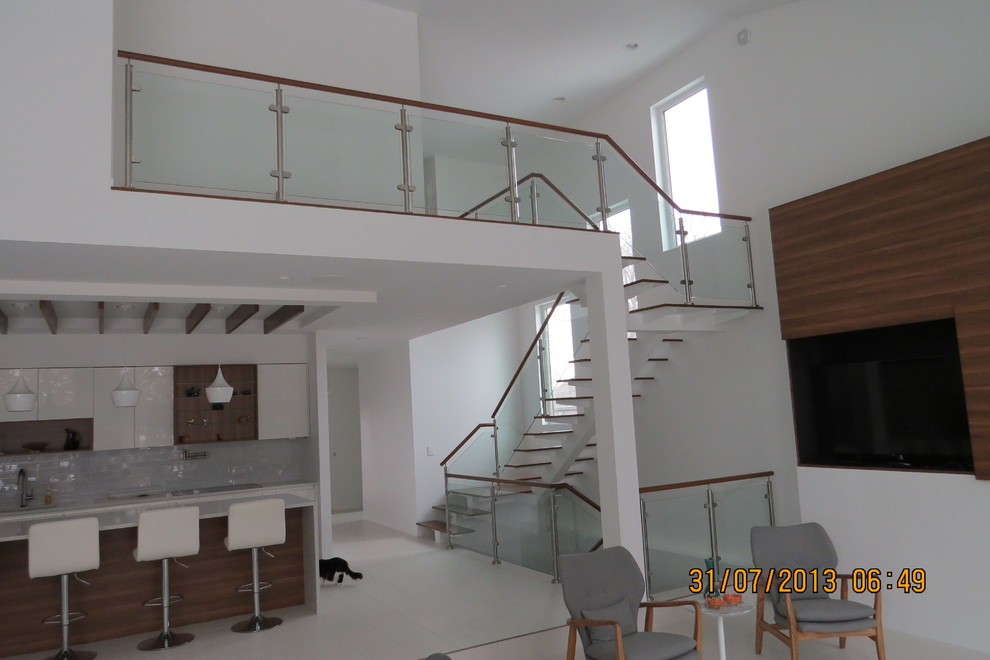 Стильный дизайн: п-образная лестница среднего размера в стиле модернизм с деревянными ступенями и стеклянными перилами без подступенок - последний тренд