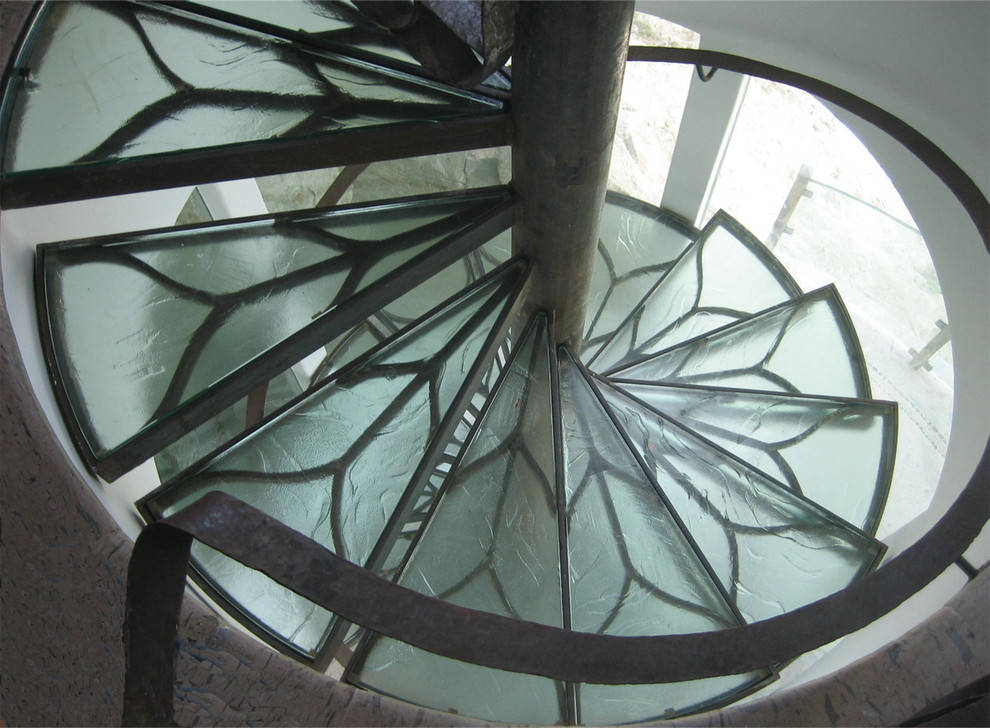 Modelo de escalera curva actual de tamaño medio con escalones de vidrio, contrahuellas de vidrio y barandilla de metal