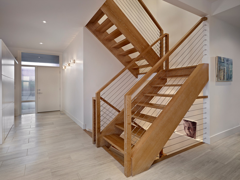 Idée de décoration pour un escalier minimaliste avec un garde-corps en câble et palier.