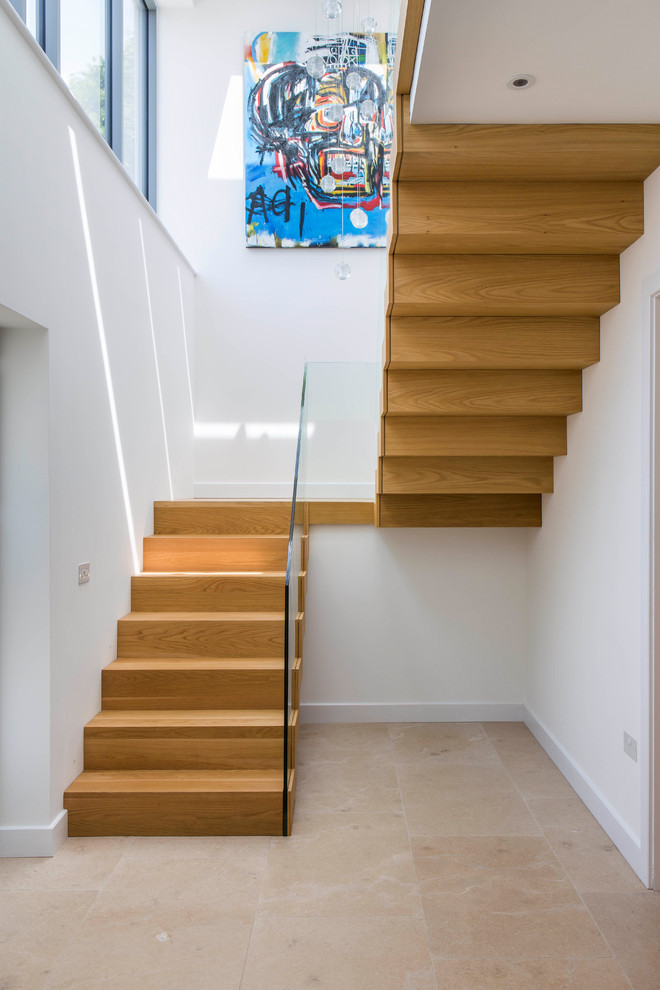 Design ideas for a medium sized wood floating glass railing staircase in Wiltshire with wood risers.