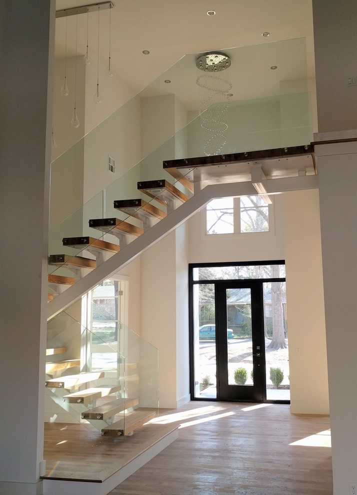 Свежая идея для дизайна: металлическая лестница на больцах в современном стиле с деревянными ступенями и стеклянными перилами - отличное фото интерьера