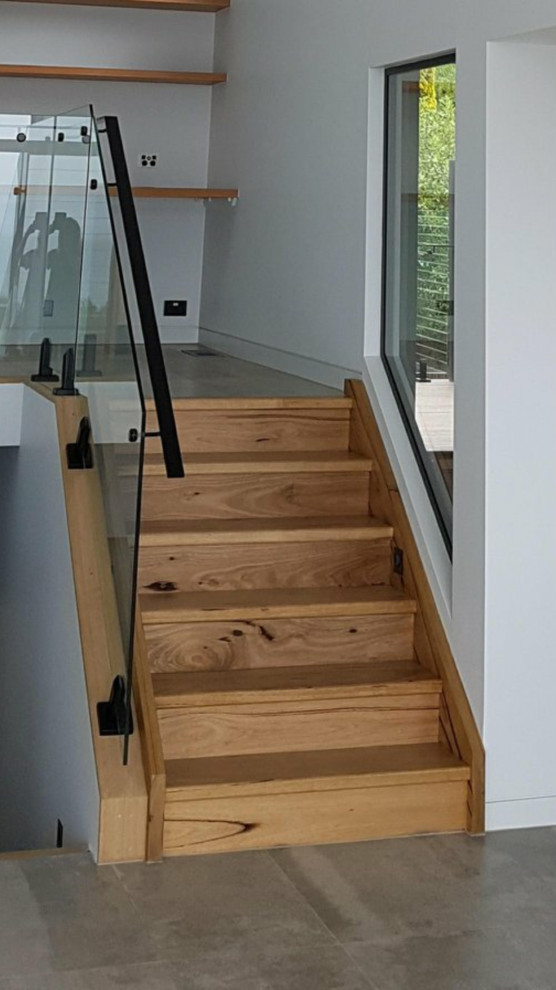 На фото: прямая деревянная лестница в стиле модернизм с деревянными ступенями и стеклянными перилами с