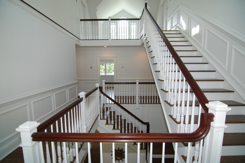 Cette photo montre un grand escalier chic en L avec des marches en bois, des contremarches en bois et un garde-corps en bois.