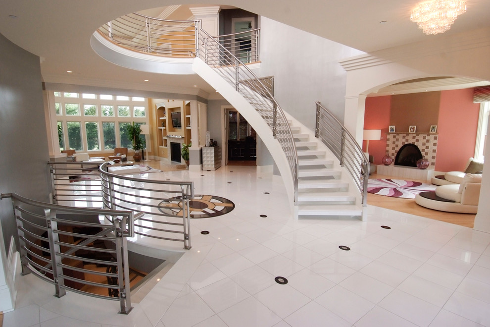 На фото: огромная изогнутая лестница в стиле неоклассика (современная классика) с акриловыми ступенями без подступенок