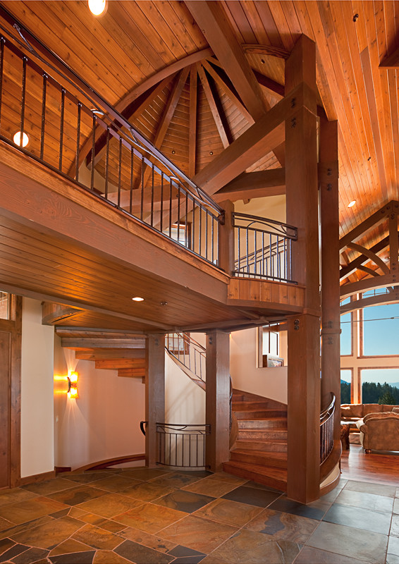 Пример оригинального дизайна: большая изогнутая деревянная лестница в стиле рустика с деревянными ступенями и металлическими перилами