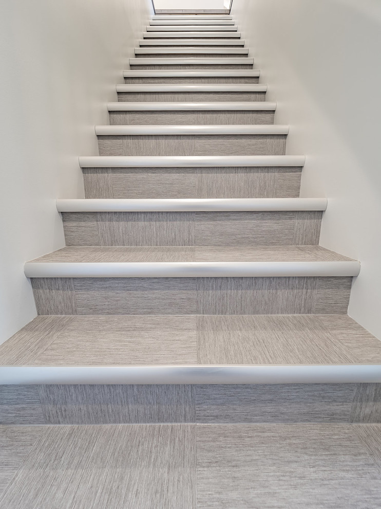 Modelo de escalera recta escandinava de tamaño medio con escalones con baldosas, contrahuellas con baldosas y/o azulejos y barandilla de metal