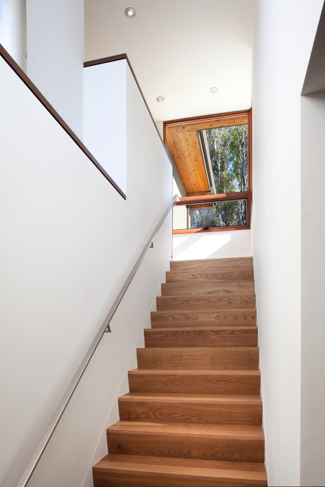 Réalisation d'un escalier droit design de taille moyenne avec des marches en bois, des contremarches en bois et un garde-corps en métal.