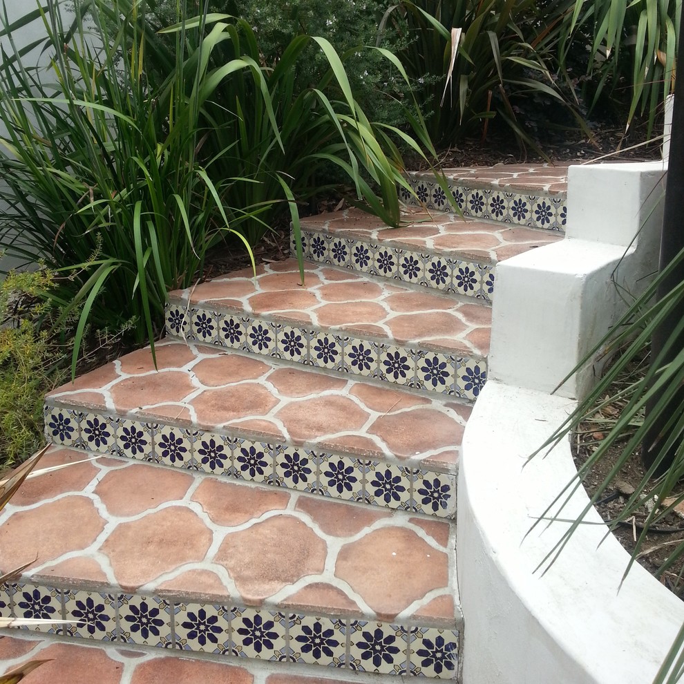 Ejemplo de escalera curva mediterránea con escalones de terracota y contrahuellas con baldosas y/o azulejos