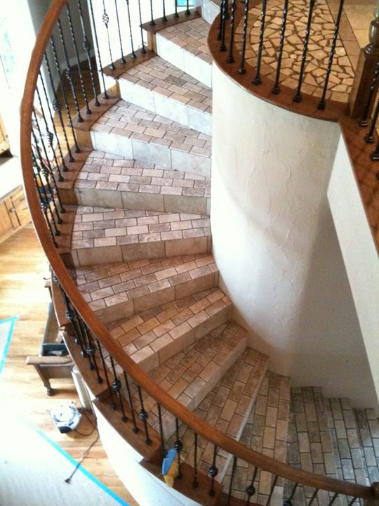 Пример оригинального дизайна: большая винтовая лестница в классическом стиле с ступенями из плитки и подступенками из плитки