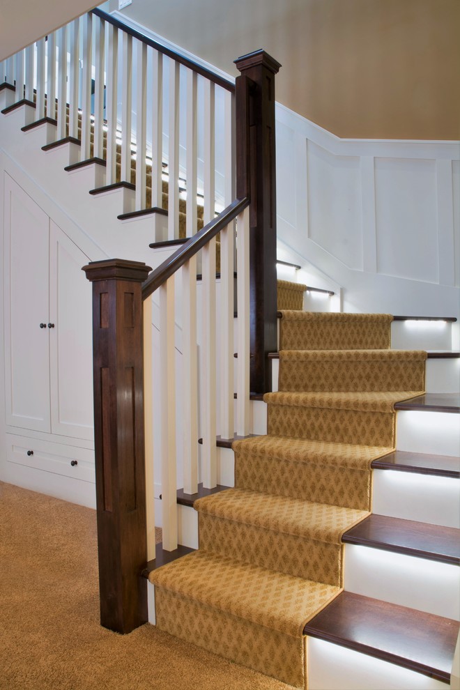 На фото: угловая лестница среднего размера в классическом стиле с ступенями с ковровым покрытием, ковровыми подступенками и деревянными перилами