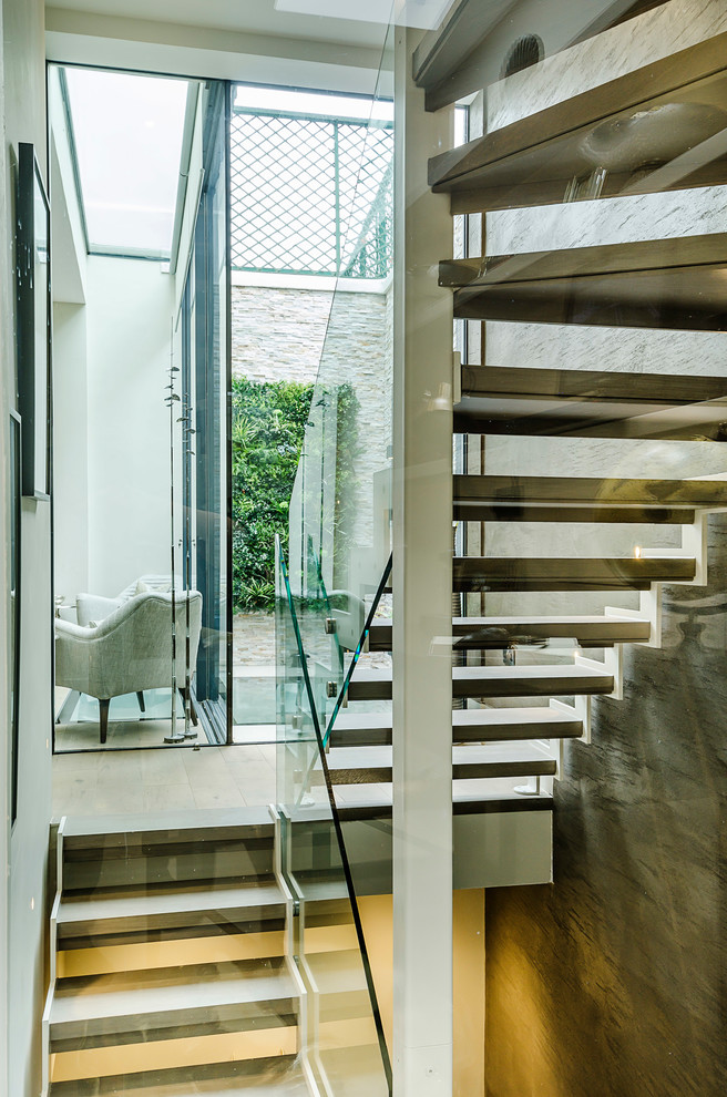 Diseño de escalera en U actual pequeña con escalones de madera, contrahuellas de metal y barandilla de vidrio