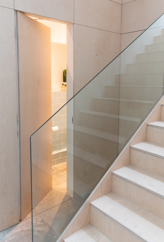 Свежая идея для дизайна: п-образная деревянная лестница в стиле модернизм с деревянными ступенями, стеклянными перилами и панелями на части стены - отличное фото интерьера