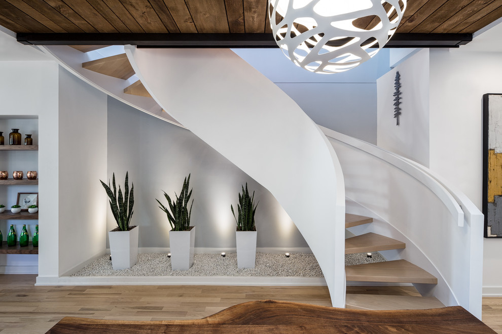Ejemplo de escalera curva minimalista de tamaño medio sin contrahuella con escalones de madera y barandilla de madera