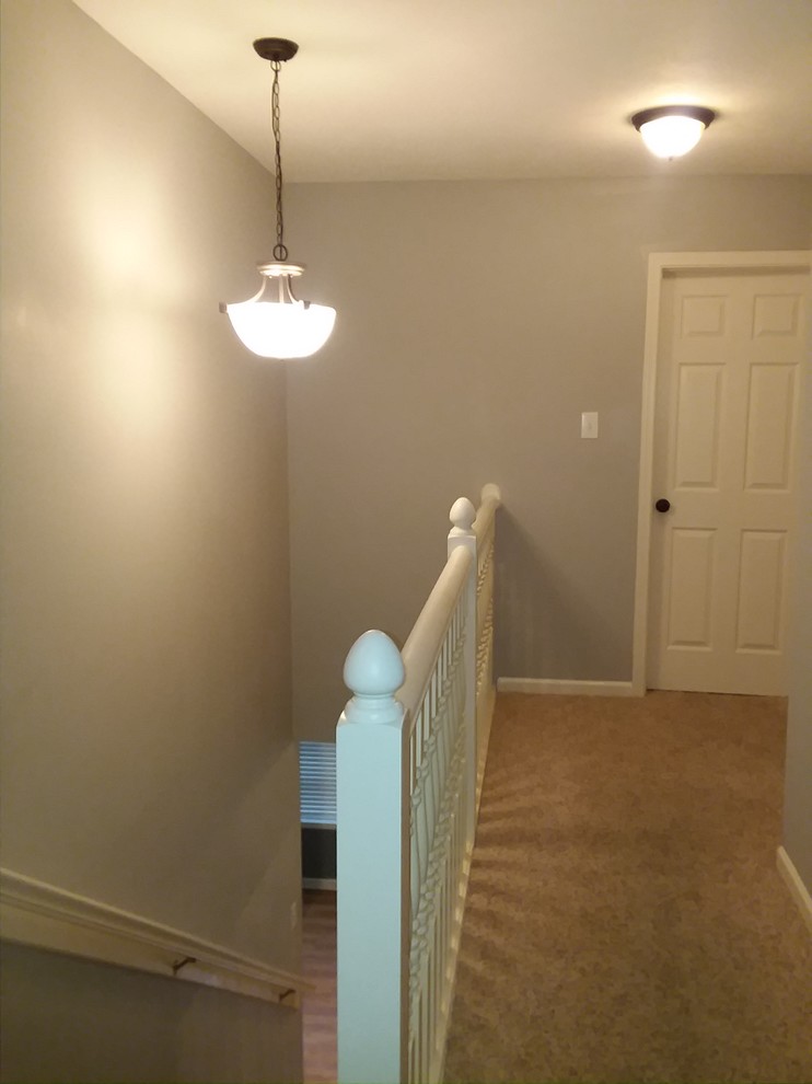 Photo of a large vintage carpeted straight wood railing staircase in Indianapolis with wood risers.