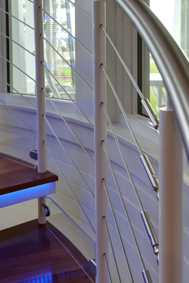 Ejemplo de escalera de caracol contemporánea de tamaño medio sin contrahuella con escalones de madera y barandilla de metal