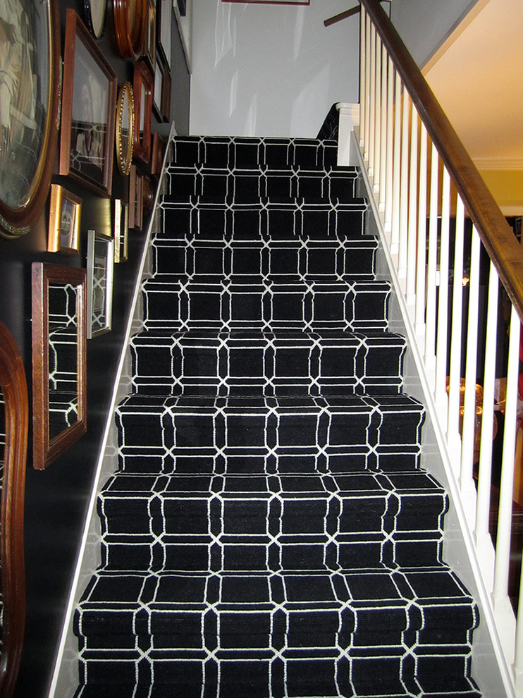 Cette photo montre un escalier chic en L de taille moyenne avec des marches en moquette, des contremarches en moquette et un garde-corps en bois.