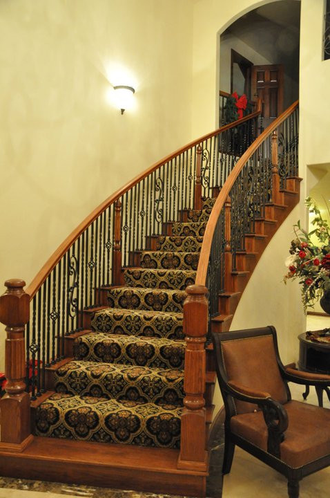 Пример оригинального дизайна: большая изогнутая лестница в классическом стиле с ступенями с ковровым покрытием и ковровыми подступенками