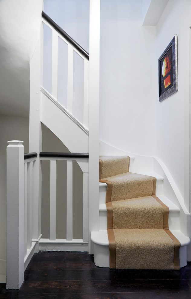 This is an example of a medium sized traditional painted wood curved wood railing staircase in London with painted wood risers.