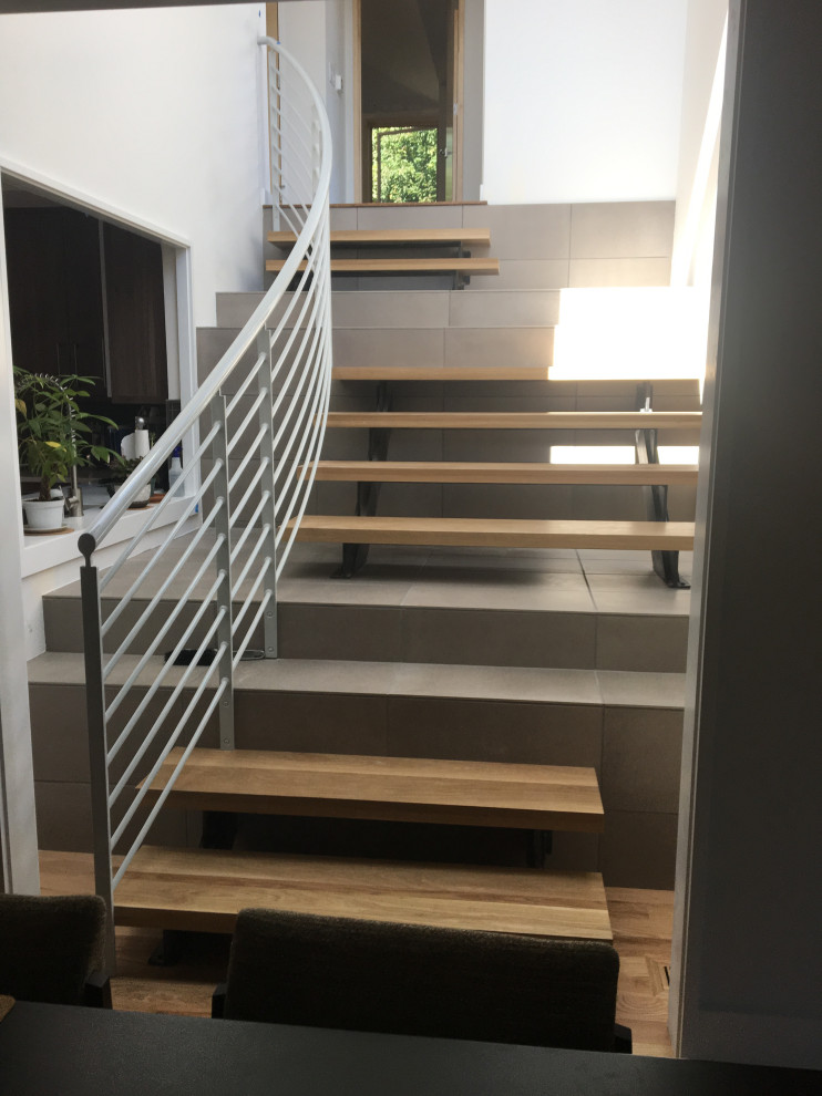 Inspiration pour un grand escalier sans contremarche courbe vintage avec des marches en bois et un garde-corps en métal.