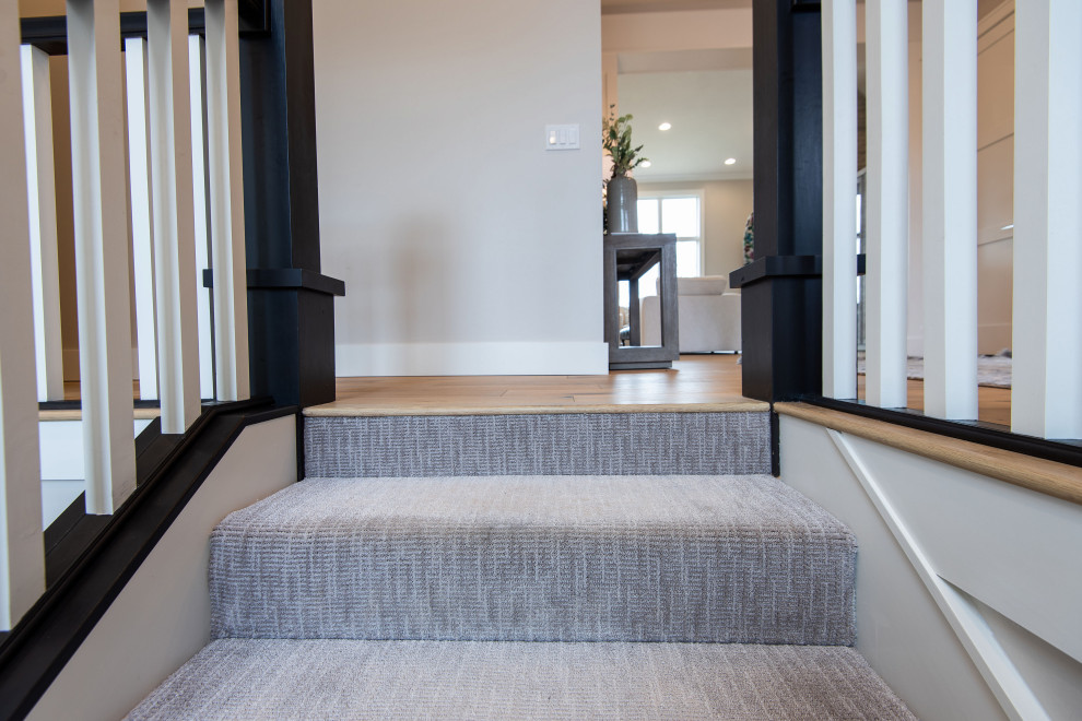 Medium sized classic carpeted straight wood railing staircase in Other with carpeted risers.
