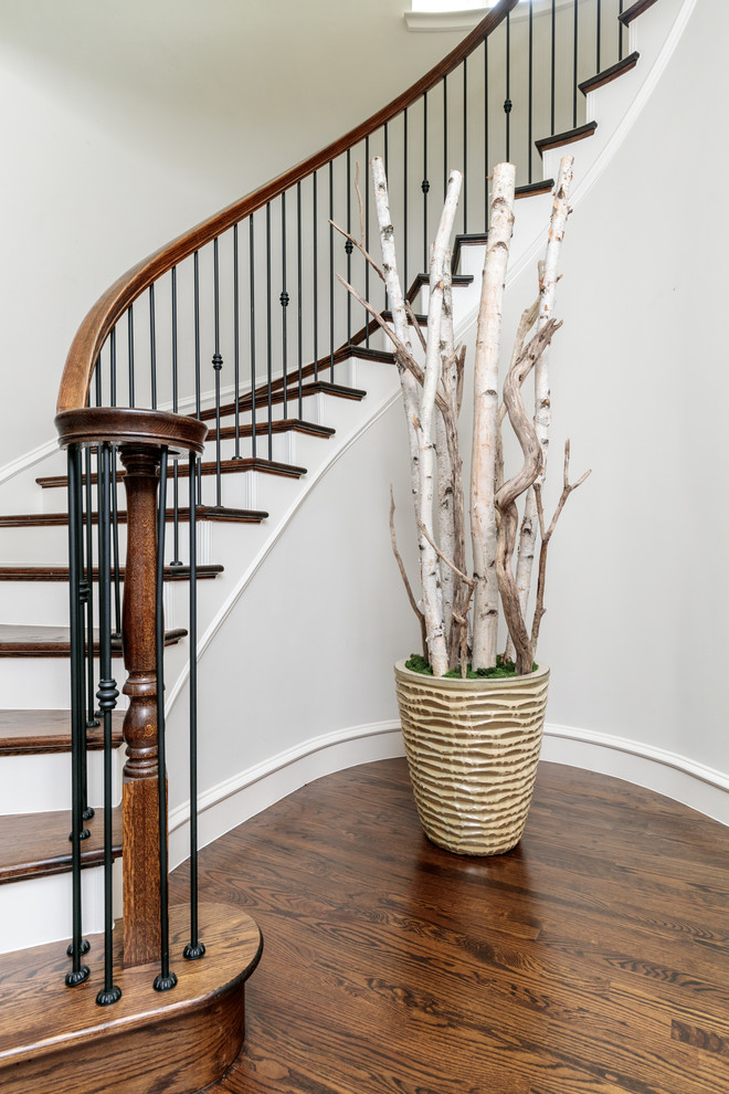 Diseño de escalera curva tradicional grande con escalones de madera, contrahuellas de madera pintada y barandilla de varios materiales