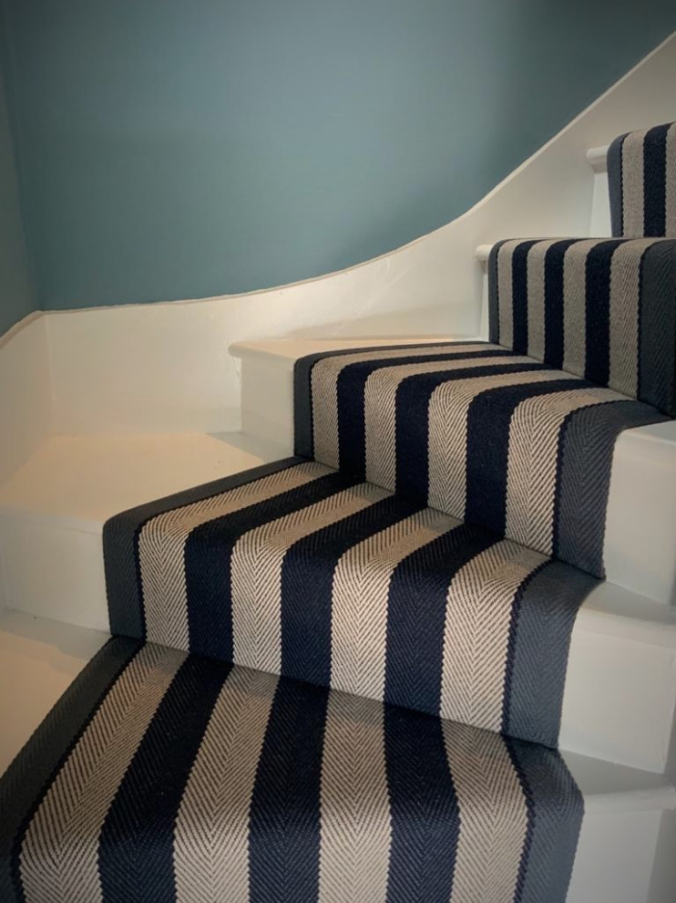 This is an example of a large contemporary carpeted curved wood railing staircase in Hertfordshire with carpeted risers.