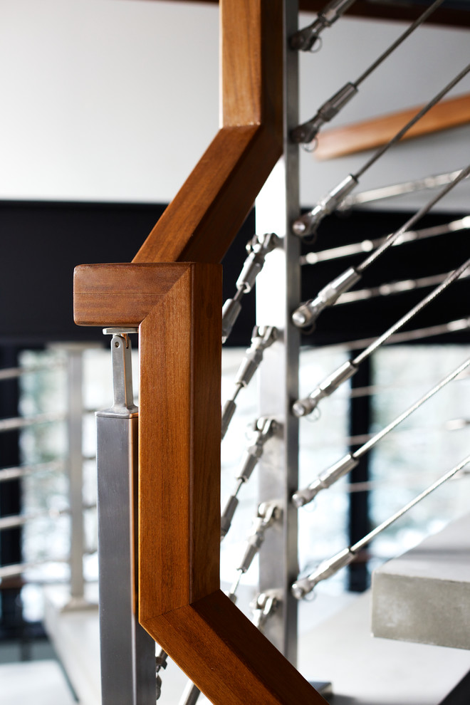 Modelo de escalera suspendida minimalista sin contrahuella con escalones de hormigón y barandilla de cable