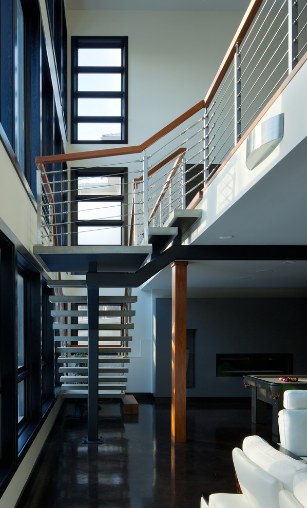 Modelo de escalera suspendida minimalista sin contrahuella con escalones de hormigón y barandilla de cable