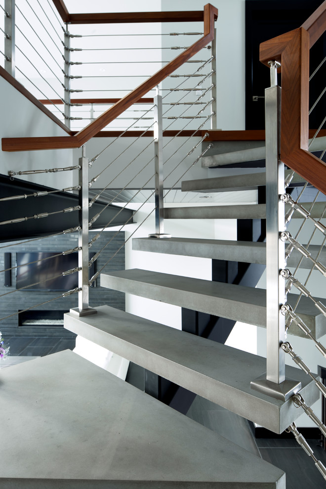 Diseño de escalera suspendida minimalista sin contrahuella con escalones de hormigón y barandilla de cable