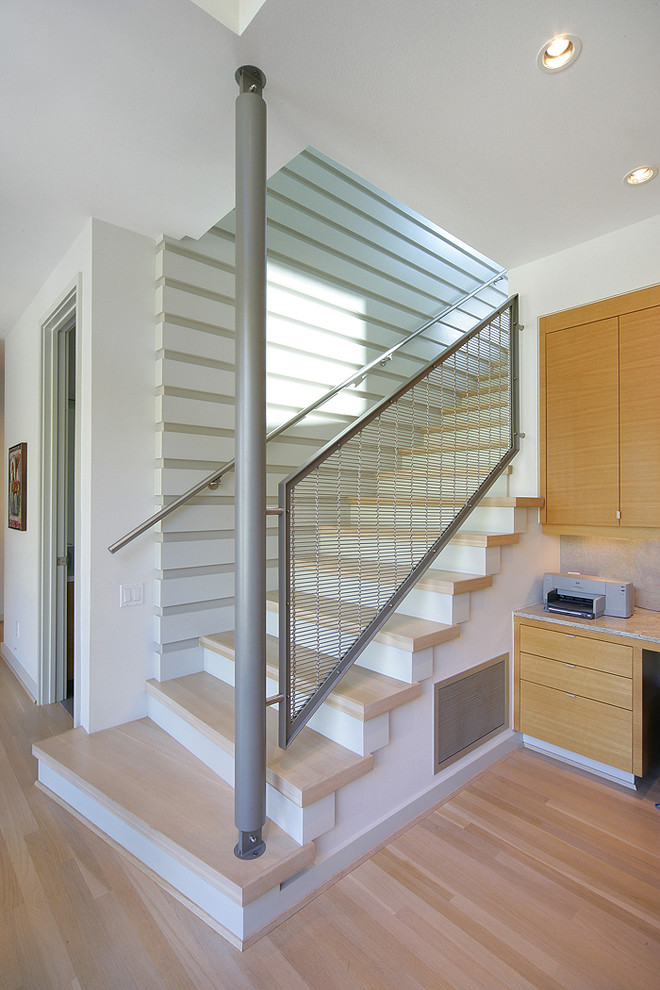 Diseño de escalera actual con escalones de madera, contrahuellas de madera pintada y barandilla de metal