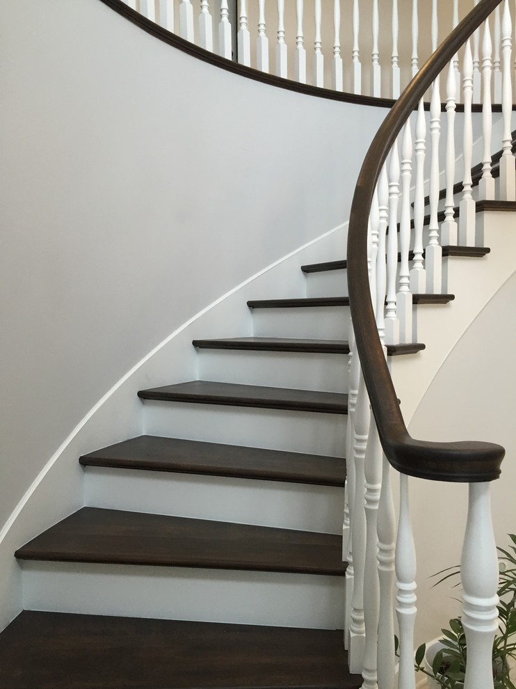Diseño de escalera curva tradicional renovada con contrahuellas de madera pintada