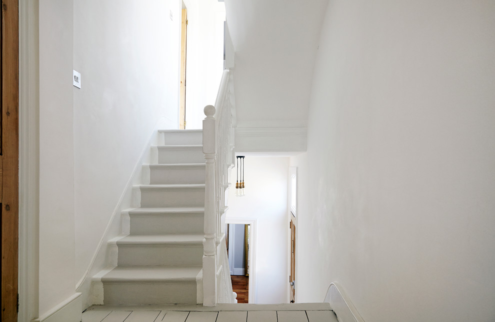 На фото: п-образная лестница в классическом стиле с крашенными деревянными ступенями и крашенными деревянными подступенками с