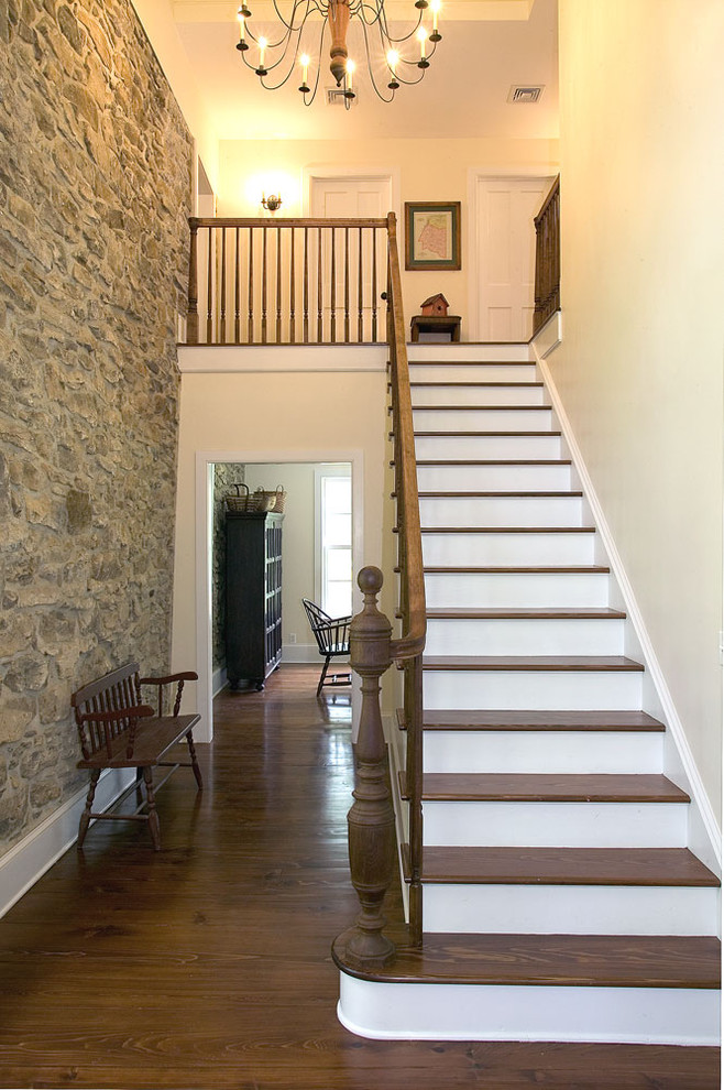 На фото: прямая деревянная лестница в стиле кантри с деревянными ступенями и деревянными перилами с