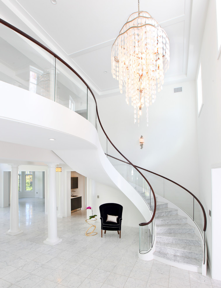 На фото: огромная лестница на больцах в современном стиле с мраморными ступенями, подступенками из мрамора и стеклянными перилами