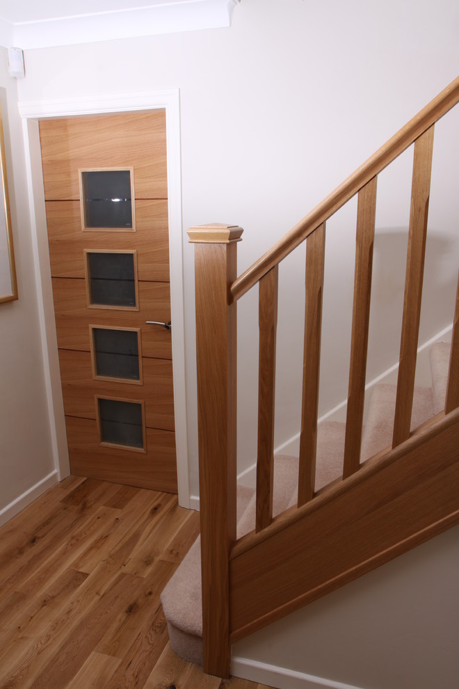 Cette photo montre un escalier tendance en U avec des marches en moquette, des contremarches en moquette et un garde-corps en bois.