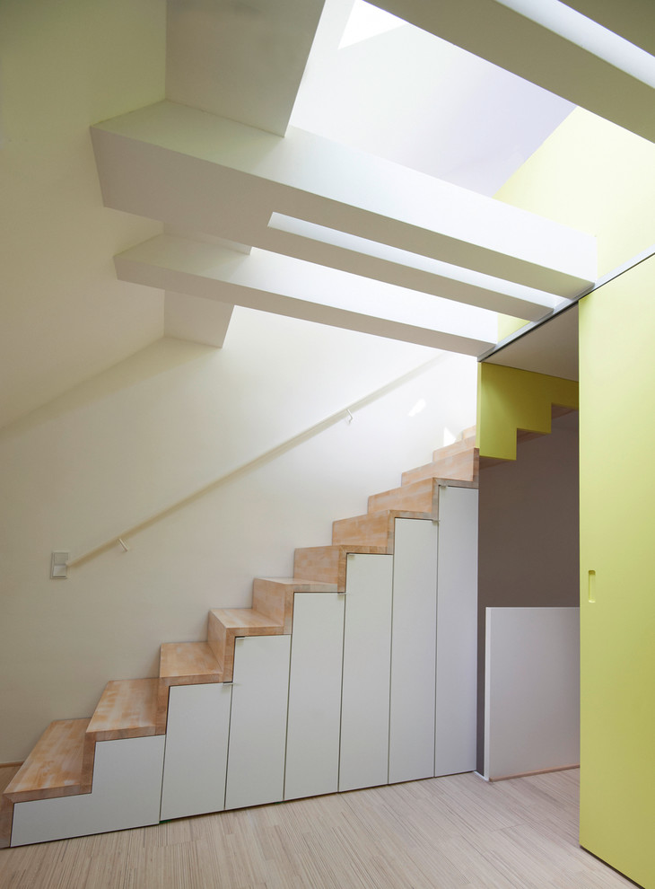 На фото: прямая деревянная лестница среднего размера в современном стиле с деревянными ступенями и кладовкой или шкафом под ней