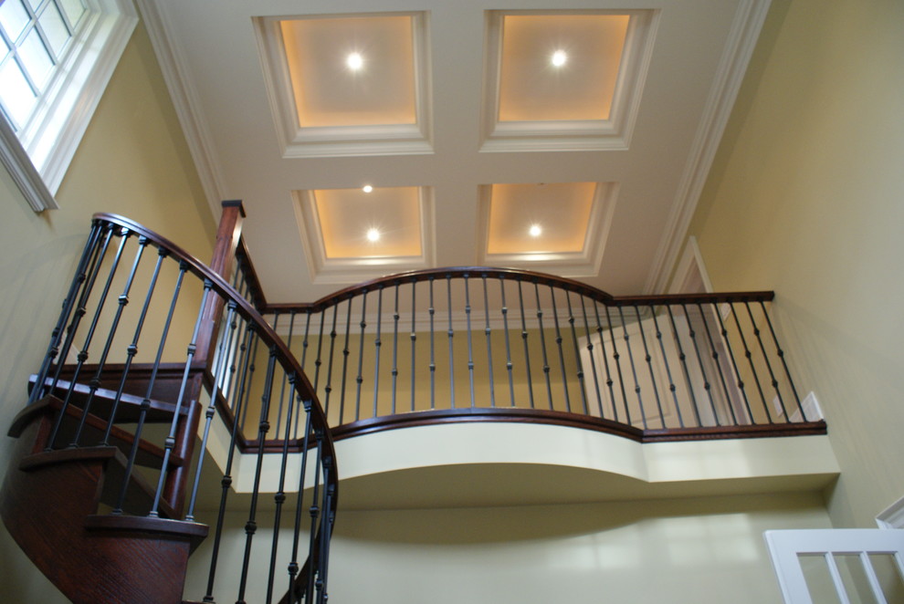 Diseño de escalera curva tradicional renovada grande con escalones de madera, contrahuellas de madera y barandilla de madera