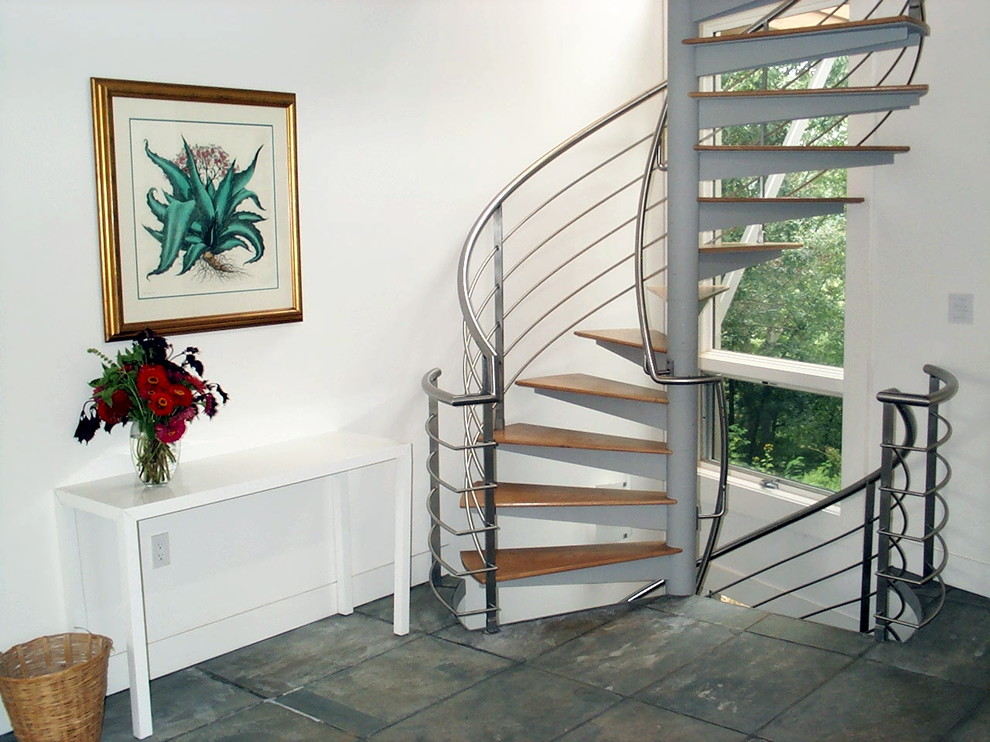 На фото: винтовая металлическая лестница среднего размера в стиле модернизм с деревянными ступенями и металлическими перилами с
