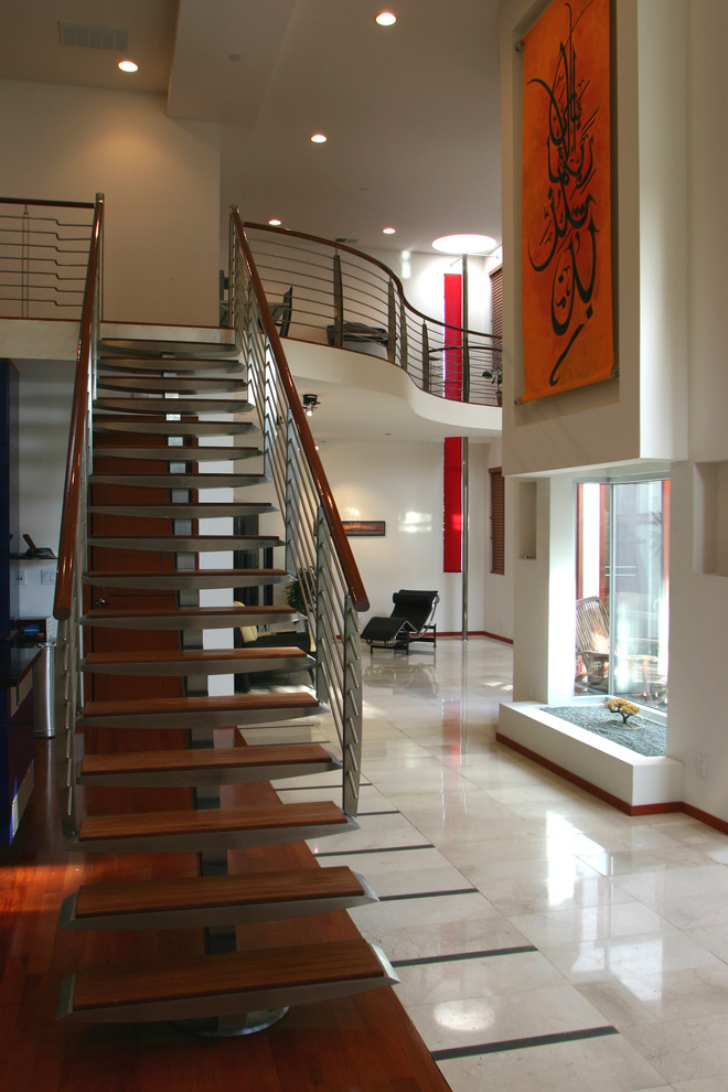 Ejemplo de escalera suspendida moderna de tamaño medio con escalones de metal, contrahuellas de madera y barandilla de metal