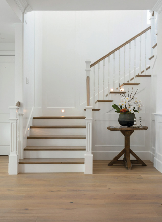 Example of a large beach style wooden u-shaped staircase design in Los Angeles with wooden risers