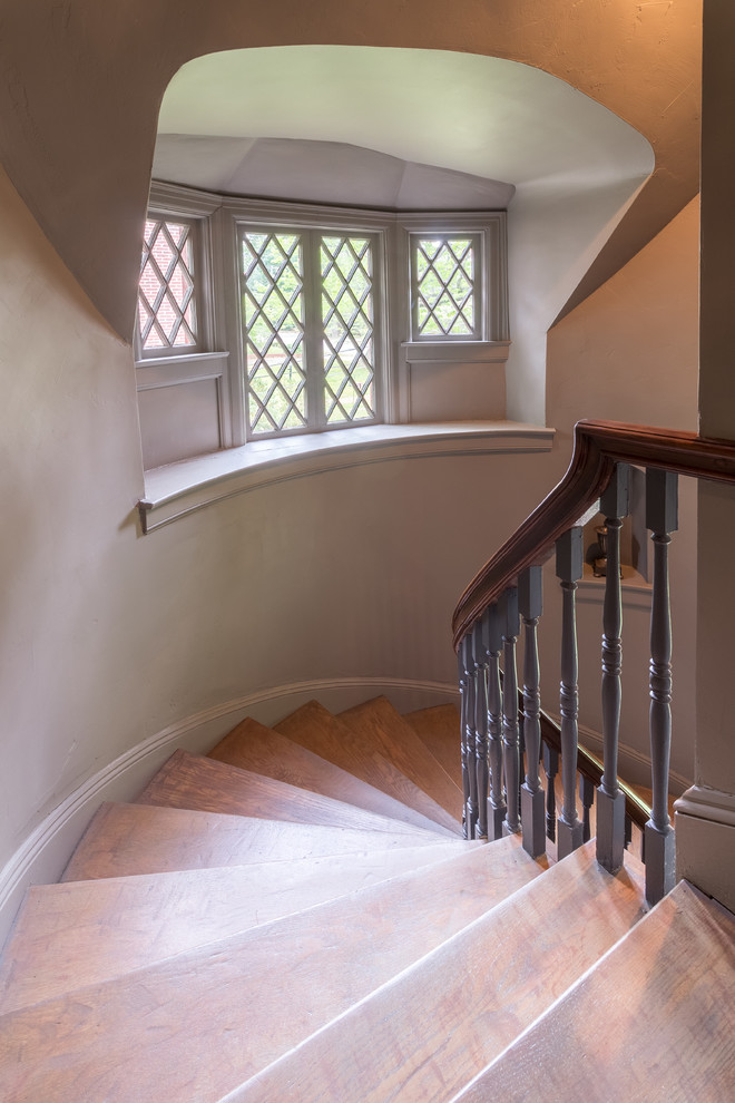 Idée de décoration pour un escalier courbe tradition avec des marches en bois, des contremarches en bois et un garde-corps en bois.