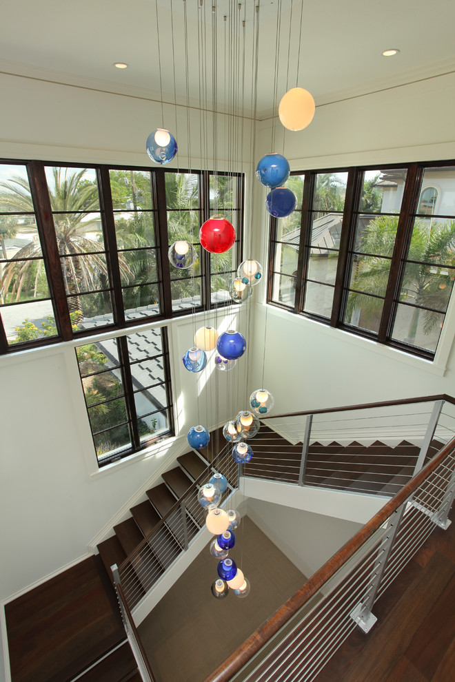 Photo of a large contemporary wood u-shaped wire cable railing staircase in Tampa with painted wood risers.
