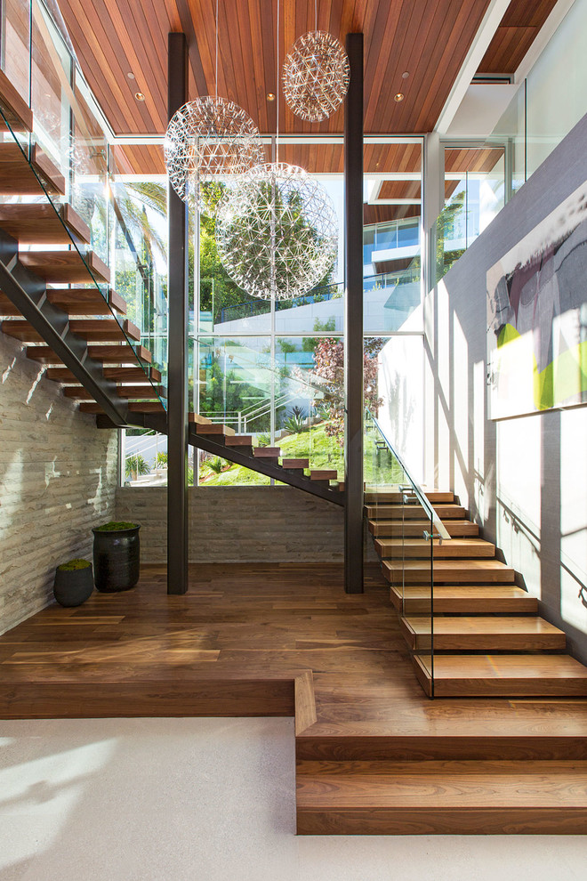 Idée de décoration pour un très grand escalier design en U avec des marches en bois, des contremarches en bois et un garde-corps en verre.