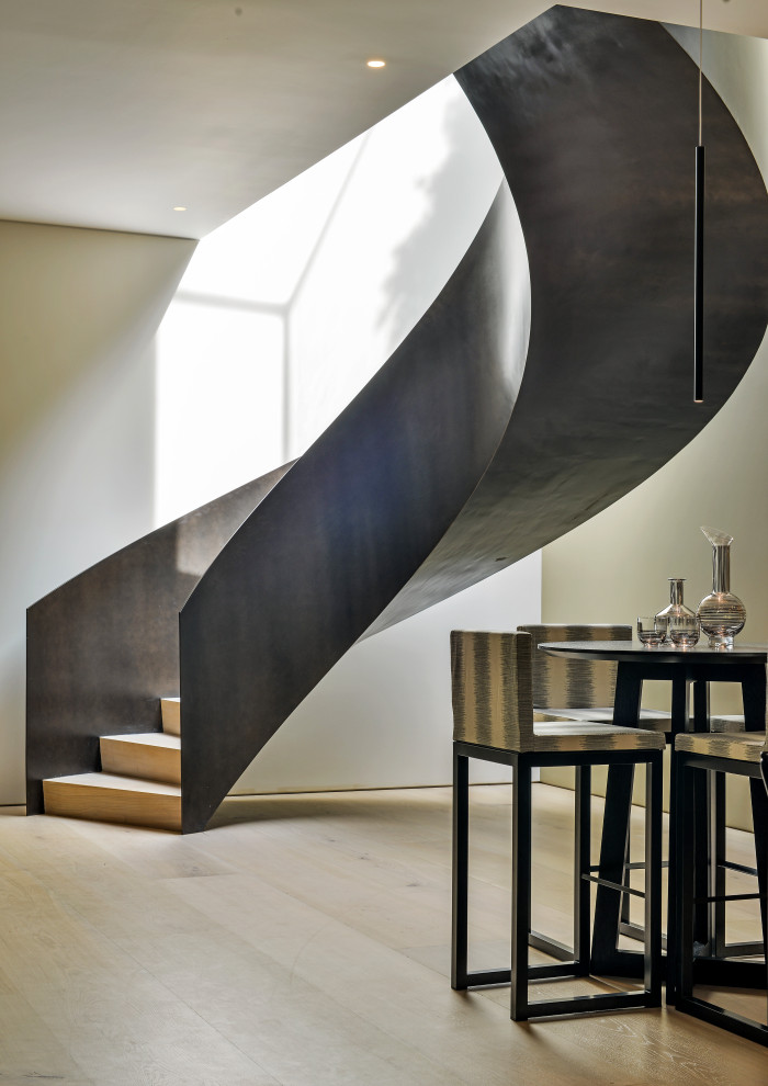 На фото: изогнутая лестница в современном стиле с металлическими перилами с