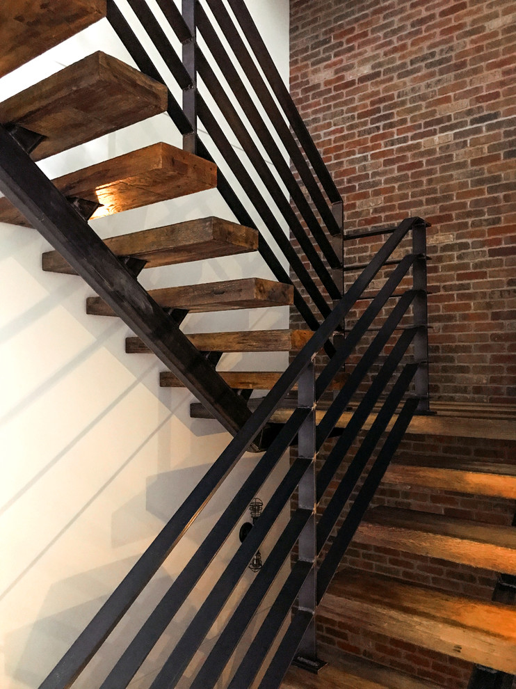 Imagen de escalera en U bohemia grande sin contrahuella con escalones de madera y barandilla de metal