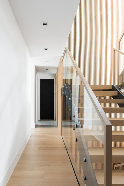 Inspiration pour un escalier minimaliste en U de taille moyenne avec des marches en bois, des contremarches en moquette et un garde-corps en verre.
