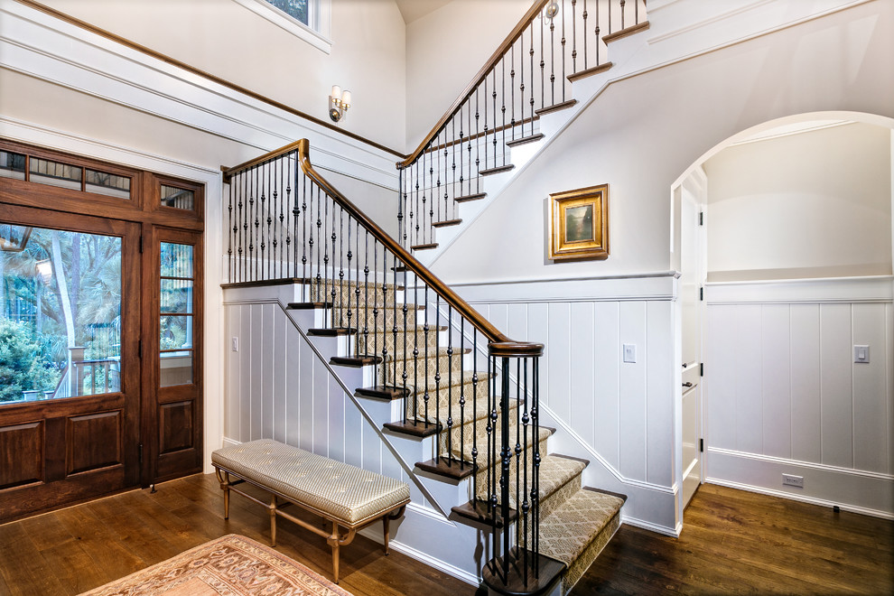 Ejemplo de escalera en U clásica renovada grande con barandilla de varios materiales, escalones de madera y contrahuellas de madera pintada